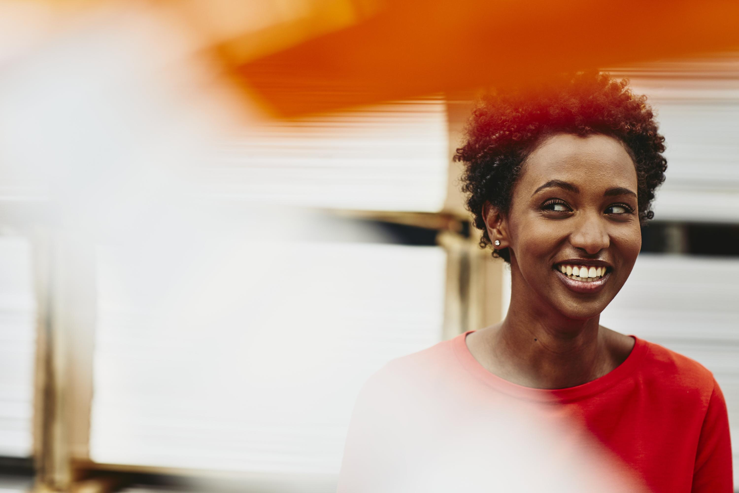 Female African-American worker. Lauging. Primary color orange. Secondary colors white/cream and red.