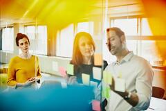 Drei Personen beim Brainstorming mit bunten Zetteln