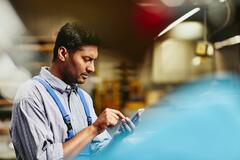 Arbeiter, der auf sein Smartphone blickt