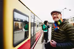 ein Mann steht auf dem Bahnsteig vor einem Zug und lächelt