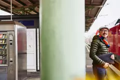 ein Mann steht auf dem Bahnsteig vor einem Zug und lächelt