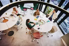 Vogelperspektive auf Menschen an runden Tischen in einem Meeting