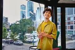 junger lächelnder Mann steht vor einer Glasfront