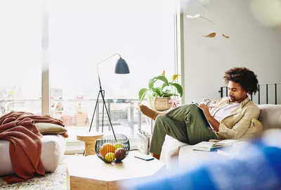 ein Mann sitzt mit einem Notizbuch auf der Couch und schreibt etwas hinein