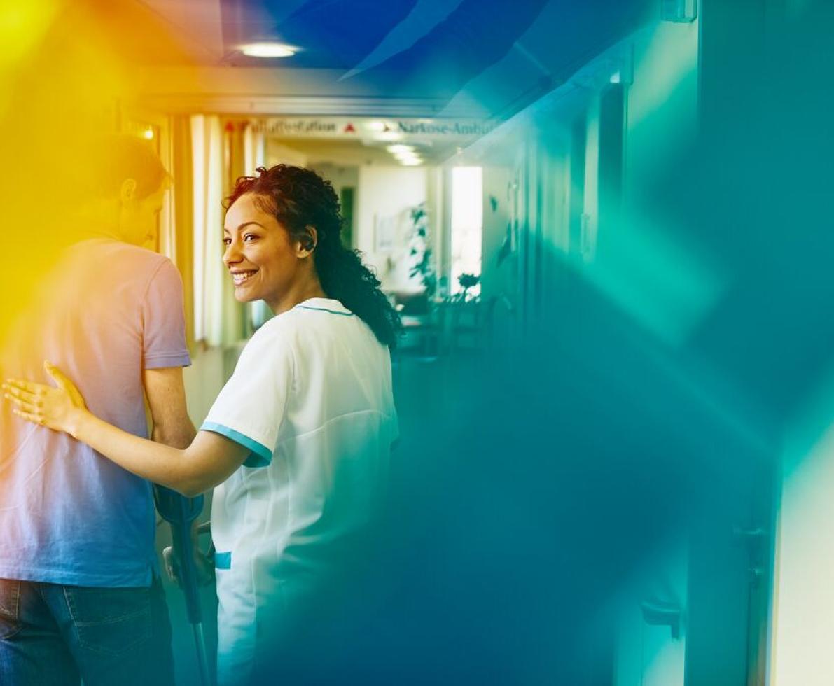 Krankenpflegerin stützt einen Mann beim Gehen