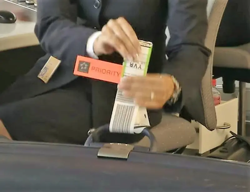Lufthansa Service-Agent klebt beim Check-In Baggage-Tag an den Koffer