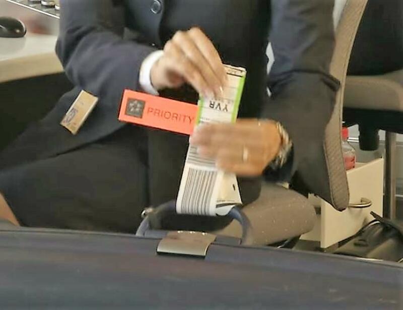 Lufthansa Service-Agent klebt beim Check-In Baggage-Tag an den Koffer