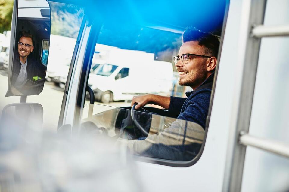 Lächelnder Mann mit Brille, der einen Lastwagen fährt.