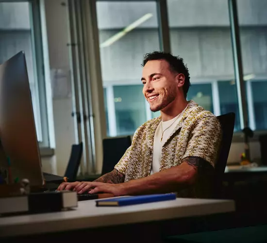 Mann blickt lächelnd auf PC Bildschirm