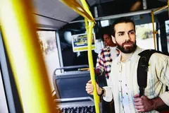 ein Mann steht in einem Bus und hält sich an der Stange fest