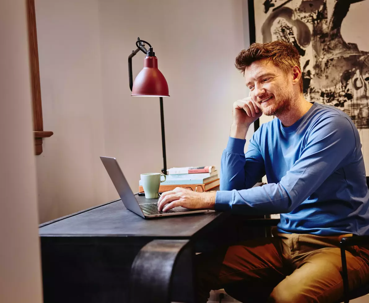 ein Mann arbeitet am Laptop und lächelt
